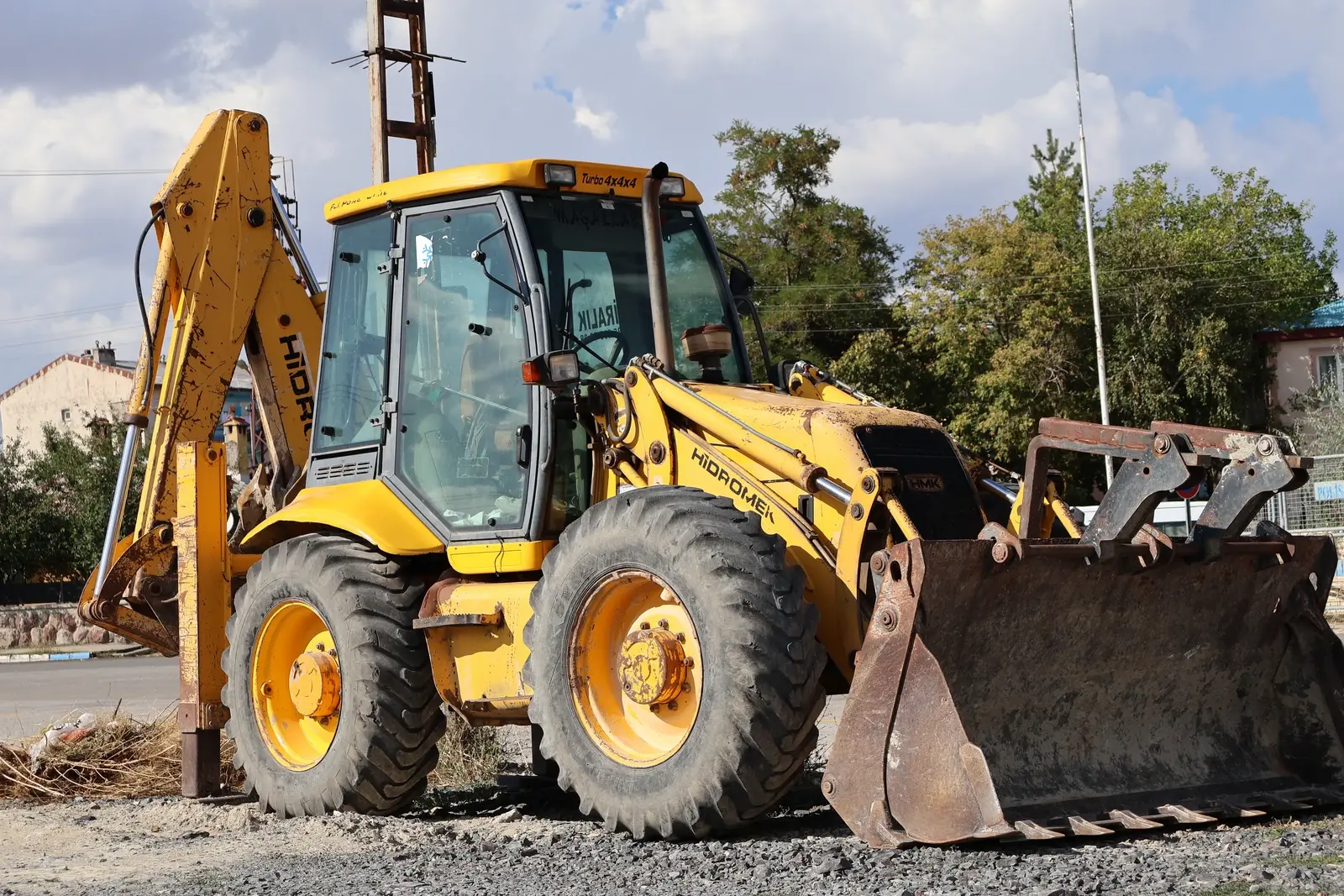 Backhoe loader from the side, cab and front bucket, ready for work